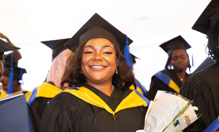Graduate smiling and holding flowers at SNHU GEM graduation ceremony